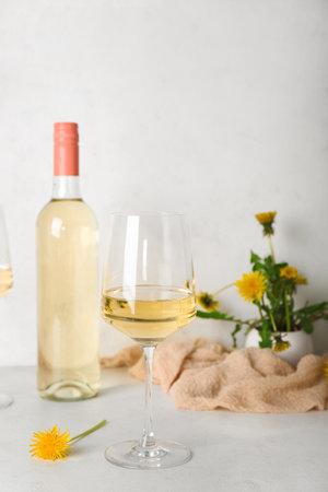 Bottle and glasses of dandelion wine on white tableの写真素材