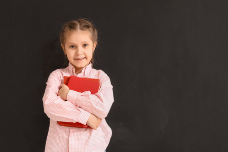 Little girl with books near blackboard. Children's Day celebrationの写真素材
