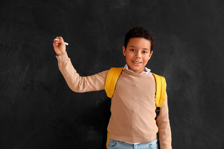 Little African-American boy with chalk piece drawing on blackboard. Children's Day celebrationの写真素材