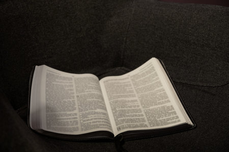 Open Holy Bible on dark armchair