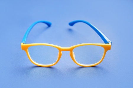 Stylish yellow eyeglasses on blue backgroundの写真素材