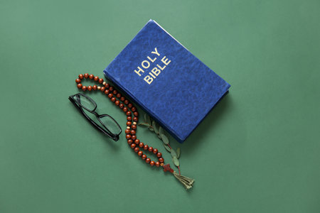 Holy Bible with eyeglasses and prayer beads on green backgroundの写真素材