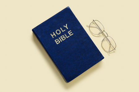 Holy Bible with eyeglasses on pale yellow backgroundの写真素材