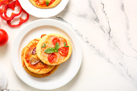 Plates with different tasty mini pizzas on white background