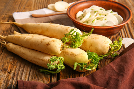 Bowl with slices of fresh daikon radish on wooden backgroundの写真素材
