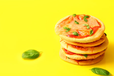 Tasty mini pizzas with basil on yellow backgroundの写真素材