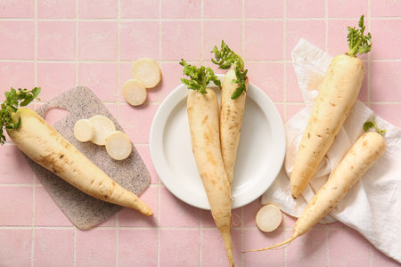 Plate and board with fresh daikon radishes on pink tile backgroundの写真素材