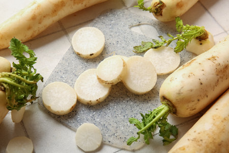 Board with fresh daikon radish on white tile backgroundの写真素材