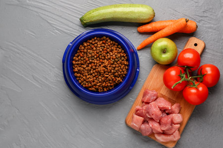 Bowl with dry pet food, raw meat and natural products on color wooden backgroundの写真素材