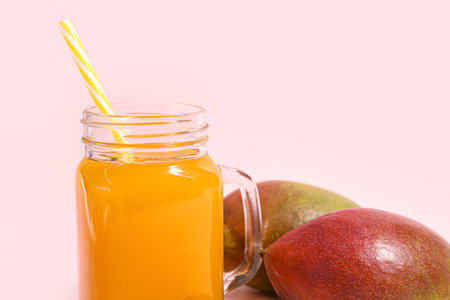 Mason jar of fresh mango smoothie on pink background, closeupの写真素材