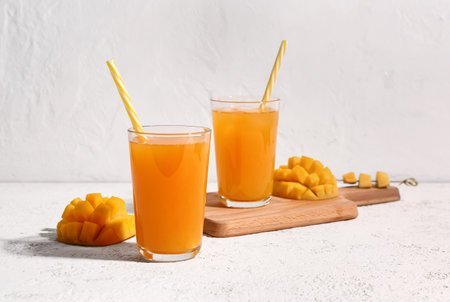 Glasses of fresh mango smoothie on light backgroundの写真素材