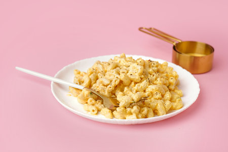 Plate of tasty Italian pasta with Cheddar cheese on pink backgroundの写真素材