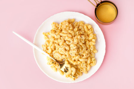 Plate of tasty Italian pasta with Cheddar cheese on pink backgroundの写真素材