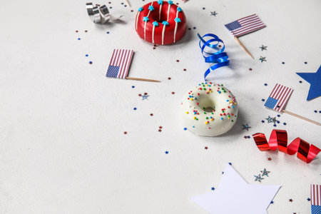 Composition with donuts, USA flags and confetti on white table. independence day celebrationの写真素材