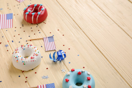 Composition with donuts, USA flags and confetti on yellow wooden table. independence day celebrationの写真素材