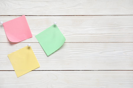 Sticky notes with pins on white wooden background