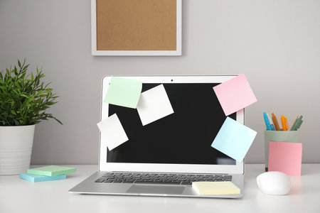 Laptop with sticky notes on white tableの写真素材