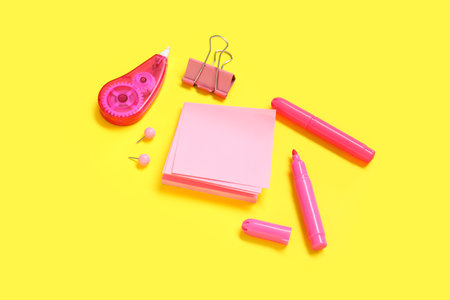 Sticky notes with different stationery supplies on yellow backgroundの写真素材