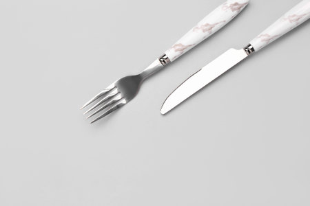 Stainless steel fork and knife with plastic handle on gray background