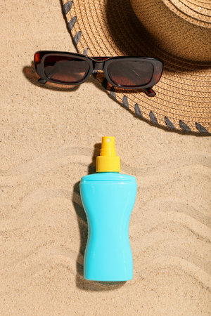 Creative composition with sunscreen cream and beach accessories on sand