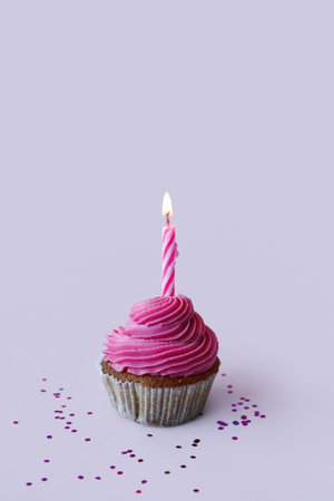 Tasty cupcake with birthday candle on lilac backgroundの写真素材