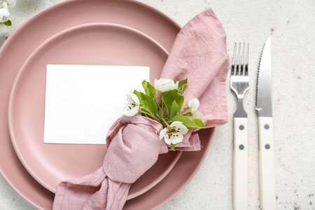 Beautiful table setting with blooming tree branch and blank invitation card on white backgroundの写真素材