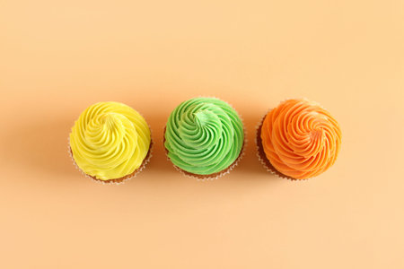 Tasty colorful cupcakes on orange background
