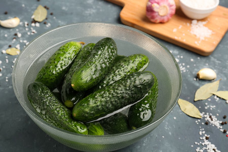 Bowl with fresh cucumbers for preservation on green backgroundの写真素材
