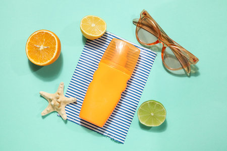 Sunscreen cream with citrus fruits, starfish and sunglasses on mint background