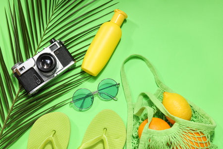 String bag with fruits, beach accessories and palm leaf on green backgroundの写真素材