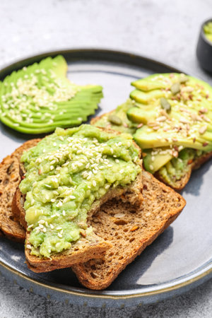 Plate of tasty avocado toasts on light background, closeup