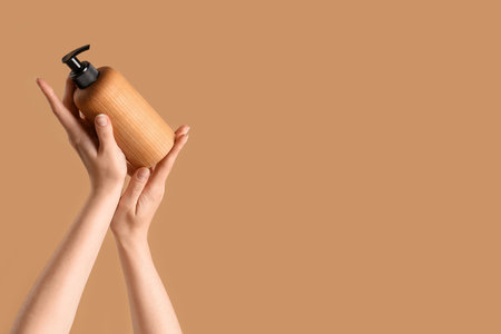 Hands holding cosmetic product on beige backgroundの写真素材