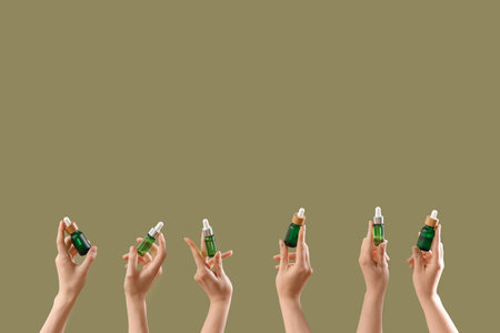 Hands holding different cosmetic products on color backgroundの写真素材