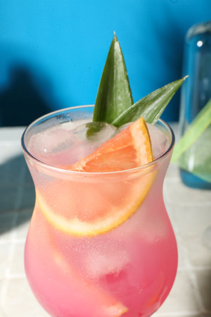 Fresh summer cocktail with grapefruit on tile table near blue wallの写真素材