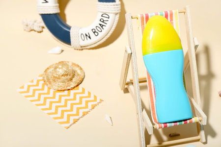 Creative composition with miniature deckchair and sunscreen on the beach