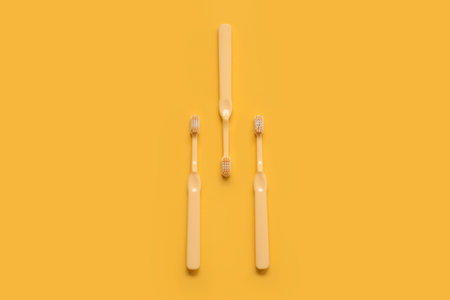 Plastic toothbrushes on yellow backgroundの写真素材