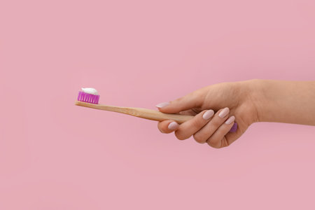 Female hand with toothbrush and paste on pink backgroundの写真素材