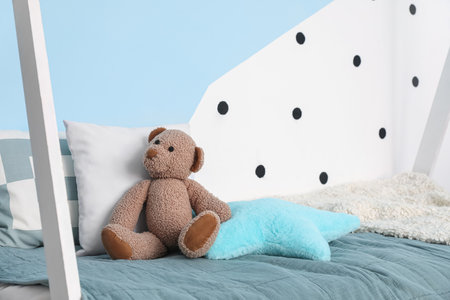 Toy bear with pillows on bed in children's roomの写真素材