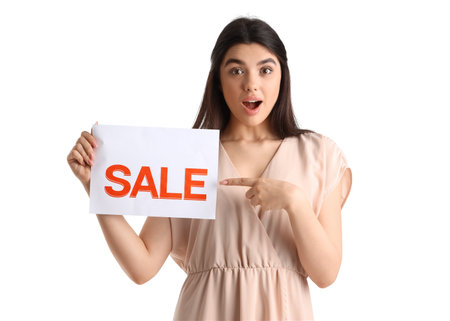 Surprised female seller pointing at sale sign on white backgroundの写真素材