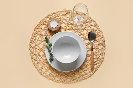 Beautiful table setting with candle and branch on beige background