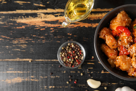 Tasty sweet and sour chicken in bowl with spices on dark wooden background, closeupの写真素材