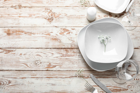 Beautiful table setting with candle and gypsophila flowers on light wooden backgroundの写真素材