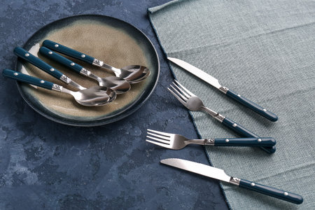 Plate with stainless steel cutlery on blue background