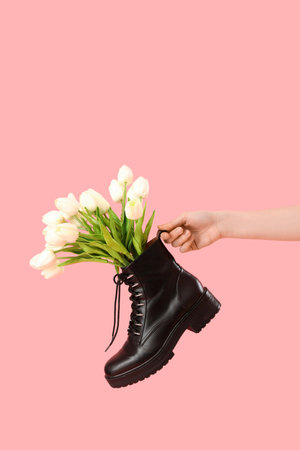 Female hand with tulip flowers in shoes on pink backgroundの写真素材