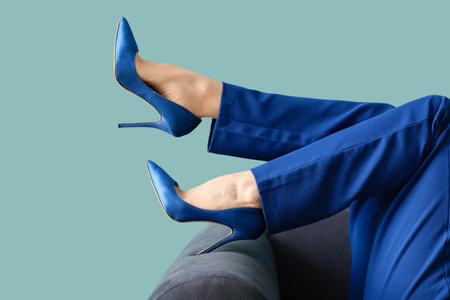Female legs in high heels on sofa against blue backgroundの写真素材