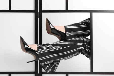 Female legs in black high heels near wallの写真素材
