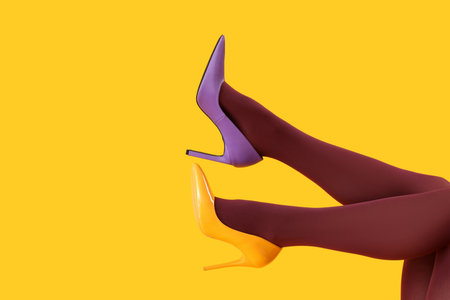 Female legs in black tights and different heels on yellow backgroundの写真素材