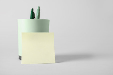 Pen holder with sticky note on gray backgroundの写真素材
