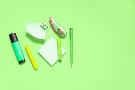 Sticky notes with different stationery supplies on green backgroundの写真素材