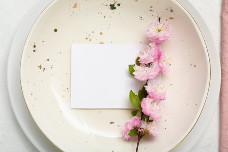 Blooming tree branch with pink flowers and invitation blank card in plate, closeupの写真素材
